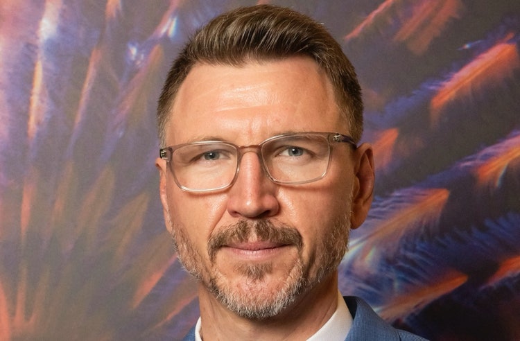 Ein Bild, das Menschliches Gesicht, Mann, Person, Lächeln enthält. Automatisch generierte Beschreibung
