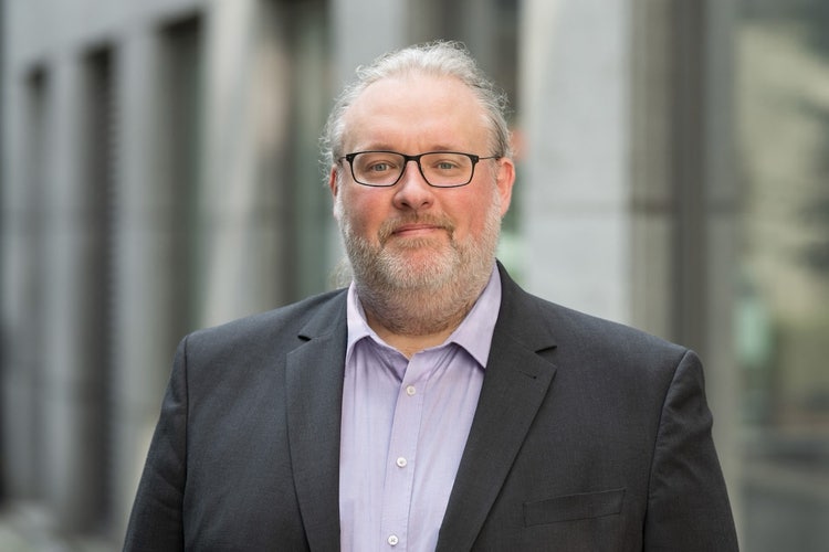 Ein Bild, das Person, Menschliches Gesicht, Mann, Kleidung enthält. Automatisch generierte Beschreibung
