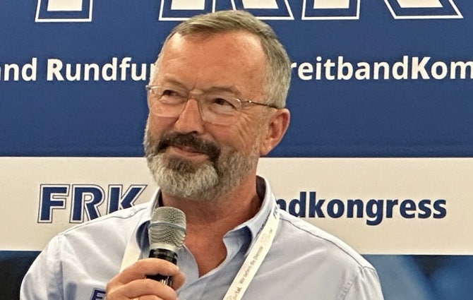 Ein Bild, das Menschliches Gesicht, Mikrofon, Person, Kleidung enthält. KI-generierte Inhalte können fehlerhaft sein.