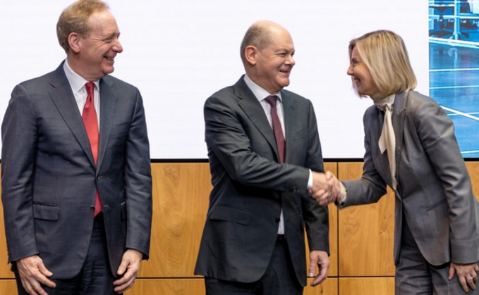 Brad Smith und Microsoft-Deutschland-Chefin Marianne Janik nehmen Bundeskanzler Olaf Scholz in ihre Mitte.
